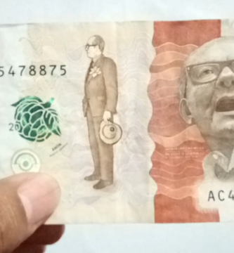 Detalle de las medidas de seguridad del billete de $20.000 pesos colombianos, incluyendo marcas de agua, cintas de seguridad y cambios de color.